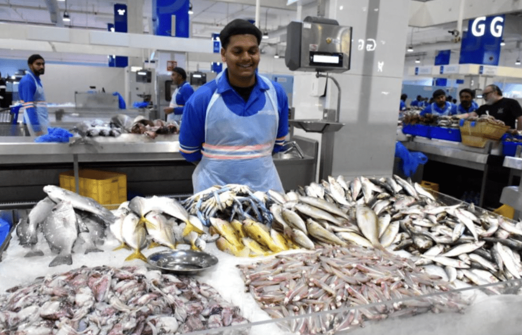Seller and fish at Deira Waterfront Fish Market in Dubai, UAE.