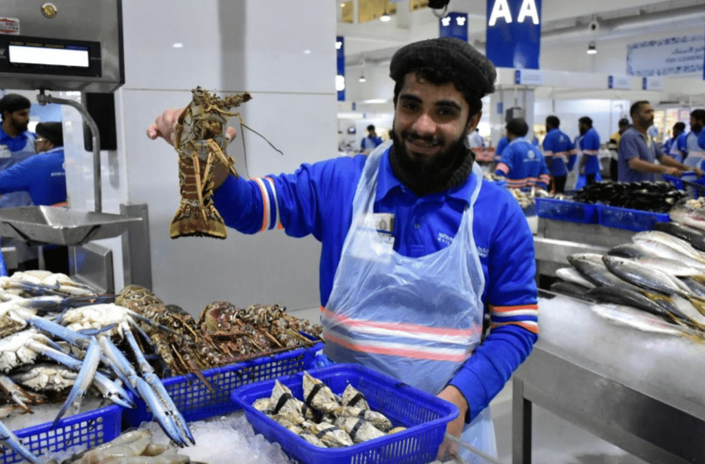 Fish seller with lobster at Deira Waterfront Fish Market in Dubai, UAE.